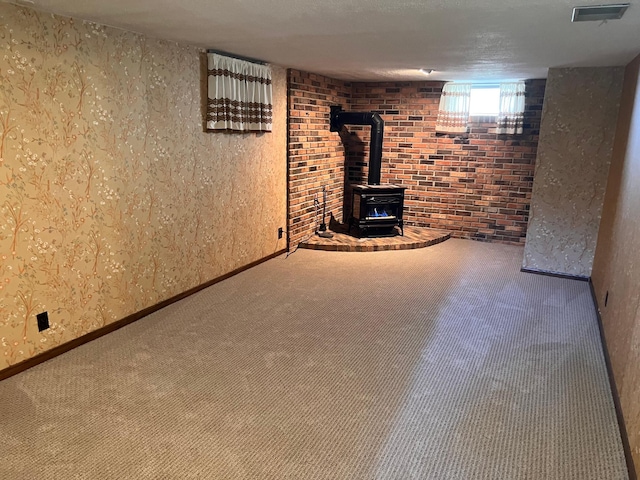 basement with a wood stove, carpet flooring, and visible vents
