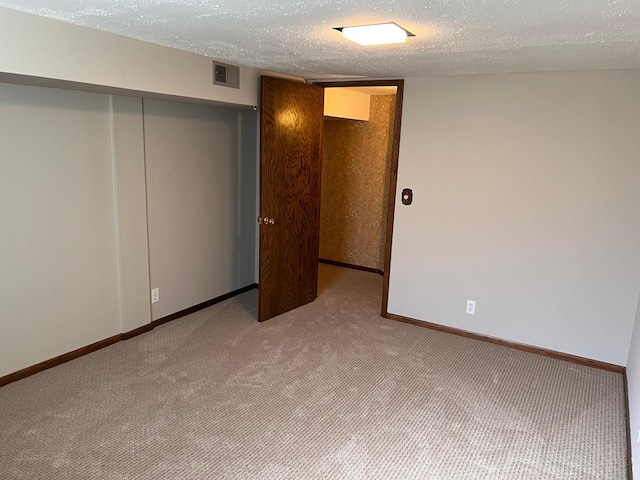 interior space with carpet flooring, a textured ceiling, baseboards, visible vents, and a closet