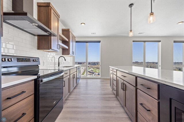 kitchen featuring a sink, wall chimney exhaust hood, a wealth of natural light, and stainless steel appliances