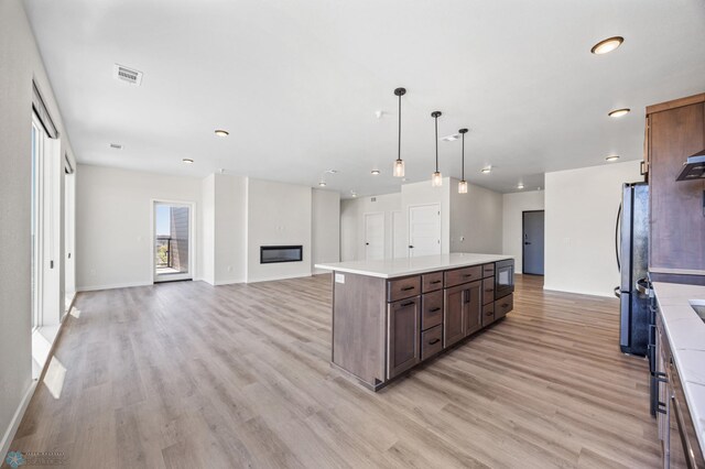 kitchen with light countertops, open floor plan, a center island, and light wood-style floors