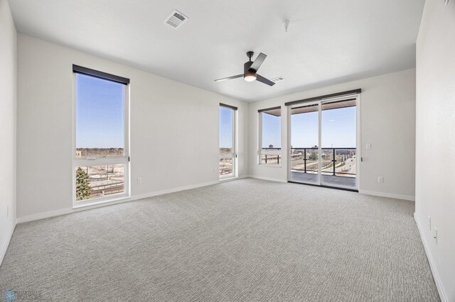 carpeted empty room with ceiling fan, visible vents, and baseboards