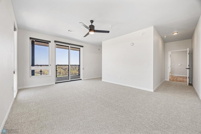 unfurnished room with baseboards, ceiling fan, light colored carpet, and visible vents