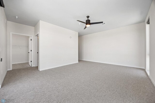 spare room with carpet flooring, ceiling fan, visible vents, and baseboards
