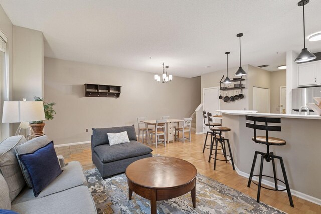 living area featuring baseboards, visible vents, light wood finished floors, and a chandelier