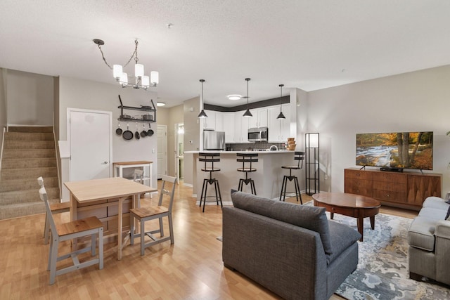 living room featuring a chandelier, stairway, and light wood-type flooring