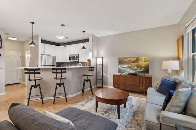 living area with baseboards and light wood finished floors