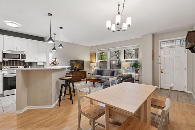 dining area with baseboards, a chandelier, and light wood finished floors