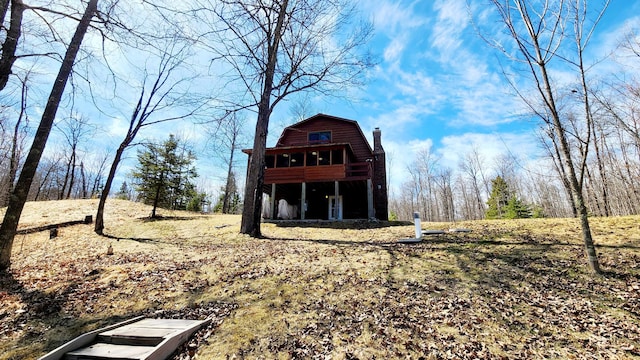 exterior space featuring a gambrel roof and a chimney