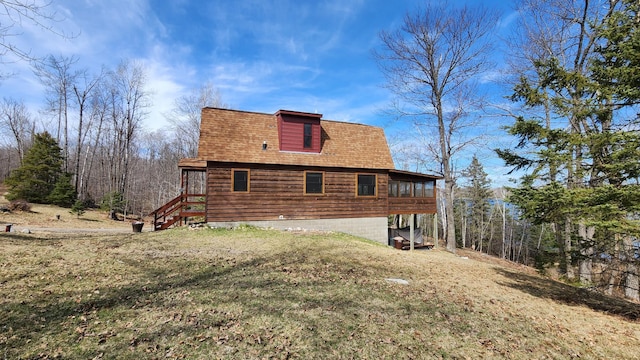 view of side of home featuring a shingled roof and a yard