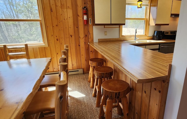 kitchen featuring a sink, a kitchen bar, wood walls, and light countertops