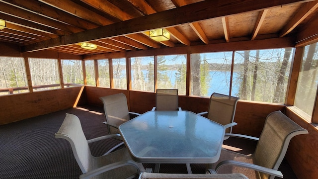 sunroom / solarium featuring a healthy amount of sunlight, outdoor dining area, and beam ceiling