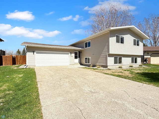 tri-level home featuring a garage, fence, a front yard, and concrete driveway