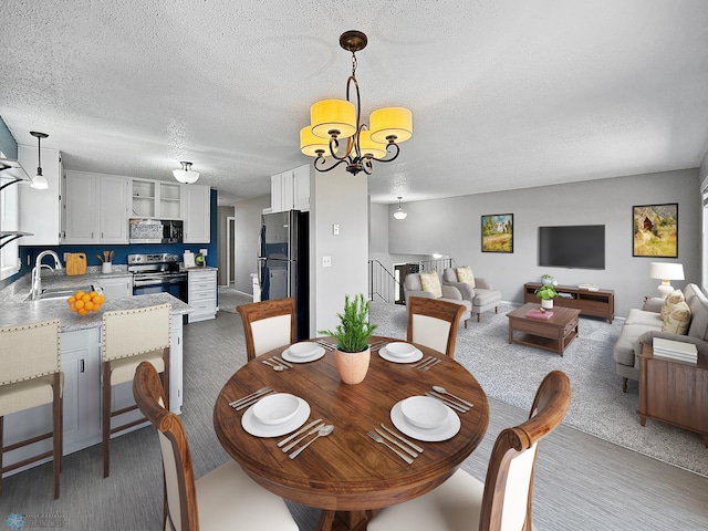 carpeted dining area featuring a textured ceiling, a notable chandelier, a sink, and stairway
