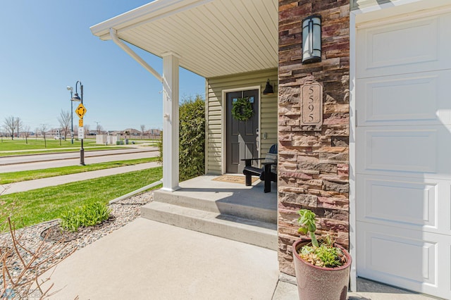 doorway to property with a porch and stone siding