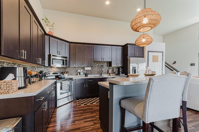 kitchen featuring dark wood-style flooring, stainless steel appliances, light countertops, and dark brown cabinets