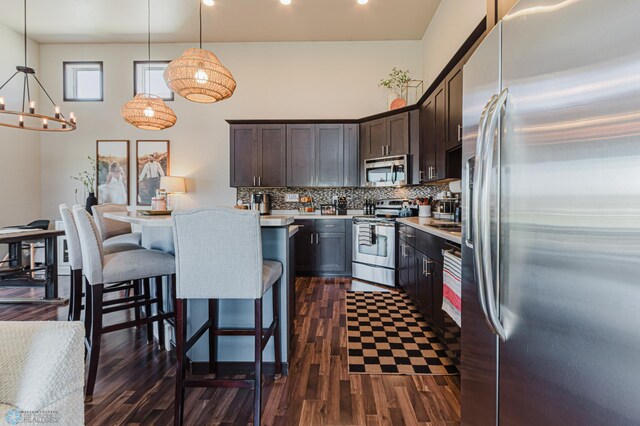 kitchen with dark wood-style flooring, dark brown cabinets, light countertops, tasteful backsplash, and appliances with stainless steel finishes