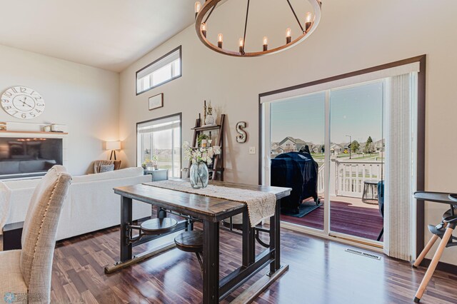 dining space featuring a notable chandelier, dark wood finished floors, a high ceiling, and visible vents