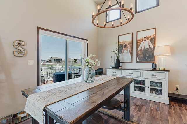 dining area with a towering ceiling, plenty of natural light, dark wood-type flooring, and a notable chandelier