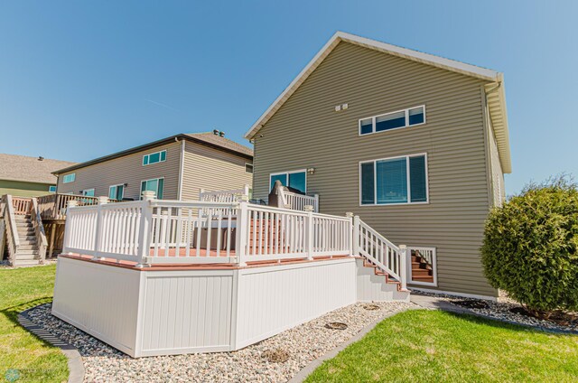 rear view of house featuring a yard, a deck, and stairs
