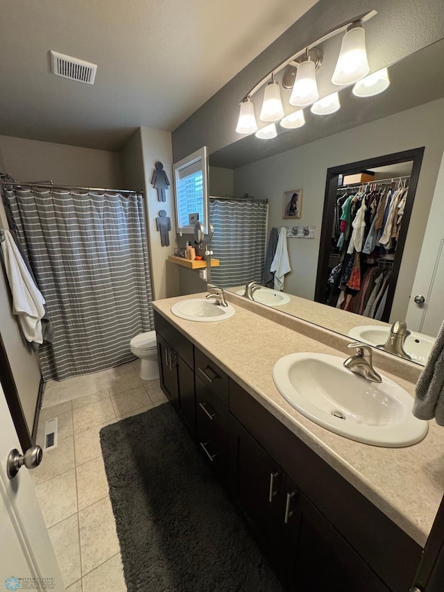 5595 Tuscan Ct S, Fargo, ND 58104 - bathroom featuring double vanity, toilet, a spacious closet, tile patterned flooring, and a shower with shower curtain