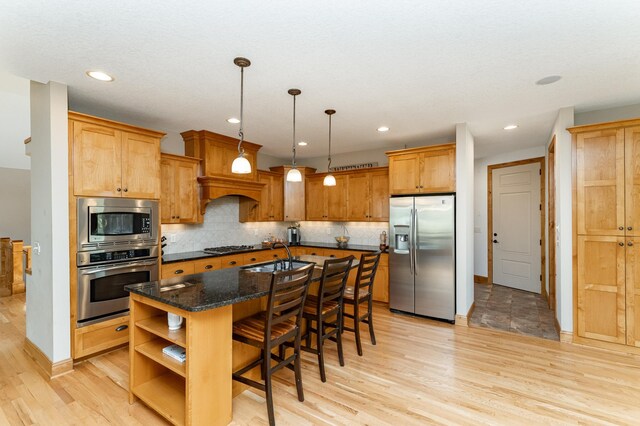 1315 Wicklow Ln SW, Rochester, MN 55902 - kitchen with stainless steel appliances, light wood-type flooring, open shelves, a breakfast bar area, and a center island with sink