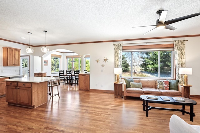 living area with a textured ceiling, decorative columns, arched walkways, and wood finished floors