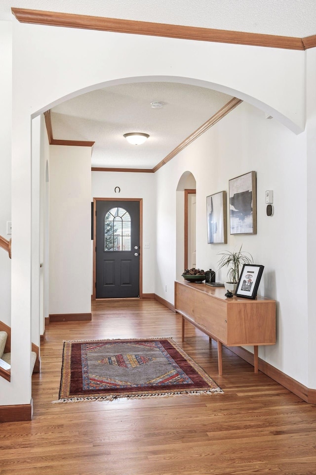 entrance foyer featuring baseboards, ornamental molding, and wood finished floors