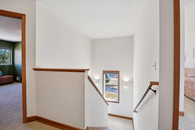 stairs featuring carpet flooring, a textured ceiling, and baseboards