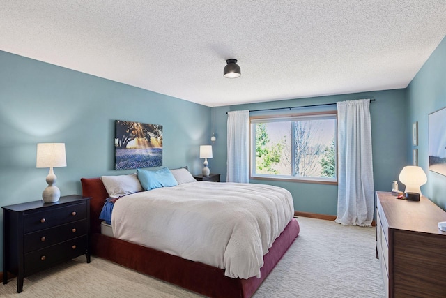 bedroom featuring baseboards, light carpet, and a textured ceiling