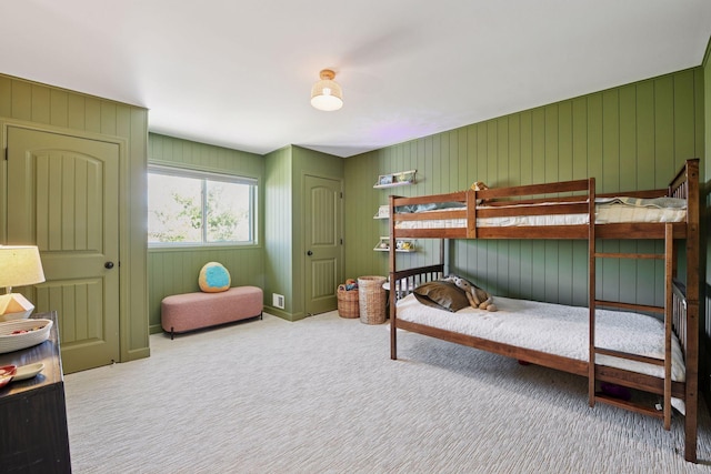 carpeted bedroom featuring wooden walls