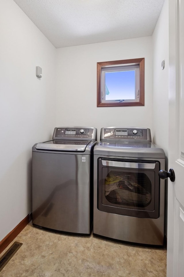 laundry area featuring a textured ceiling, washing machine and clothes dryer, laundry area, and visible vents