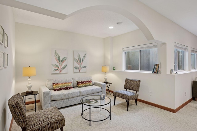 carpeted living room with recessed lighting, baseboards, and arched walkways