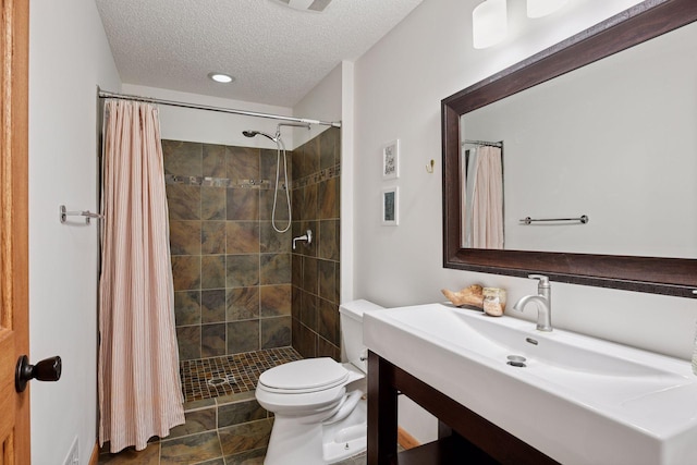 bathroom featuring a textured ceiling, a stall shower, vanity, toilet, and recessed lighting