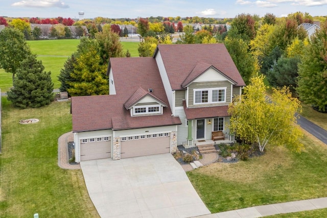 craftsman-style house featuring a front yard, driveway, stone siding, and a garage