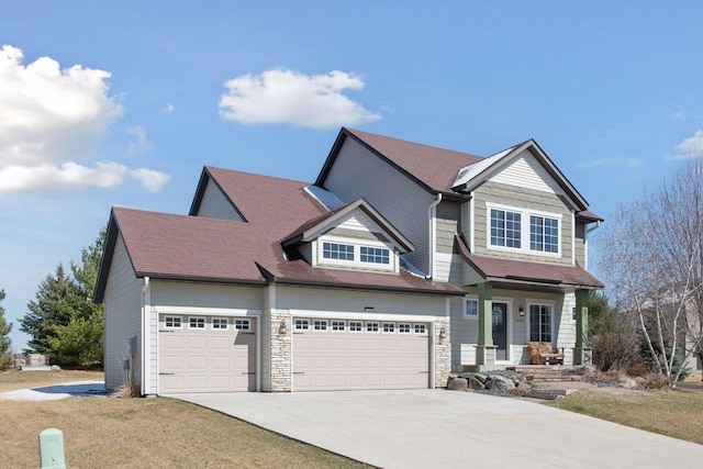 craftsman-style home with an attached garage, driveway, and stone siding