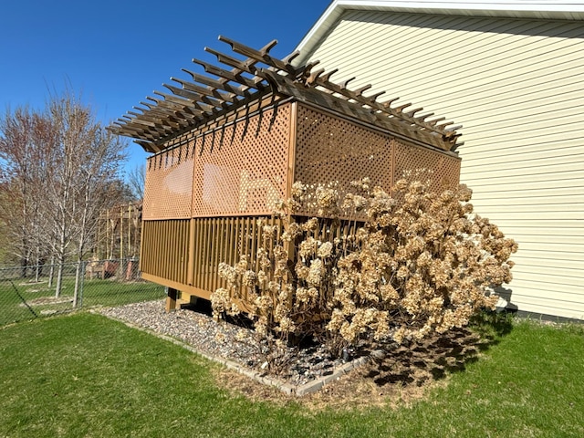 view of side of property featuring fence, a pergola, and a lawn