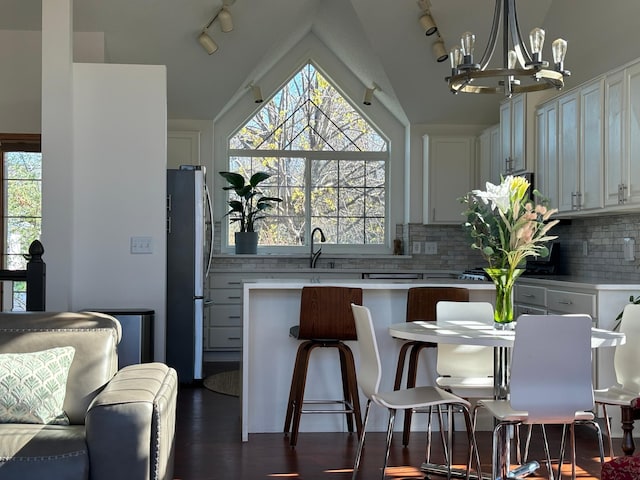 kitchen featuring an inviting chandelier, light countertops, rail lighting, freestanding refrigerator, and vaulted ceiling