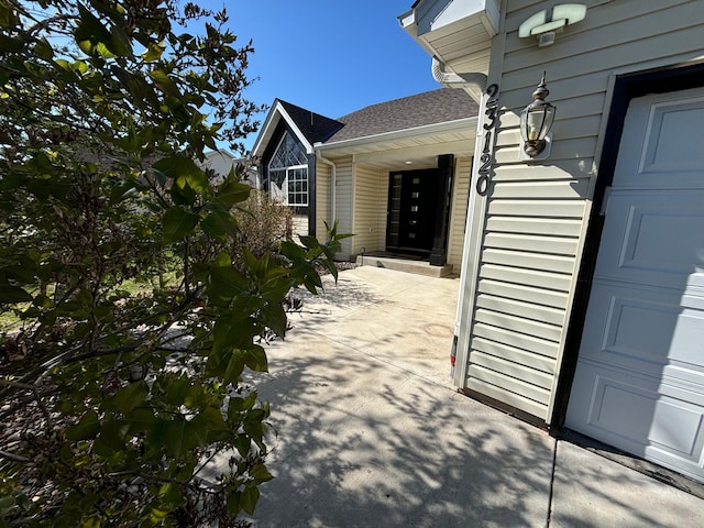 property entrance with roof with shingles and a garage