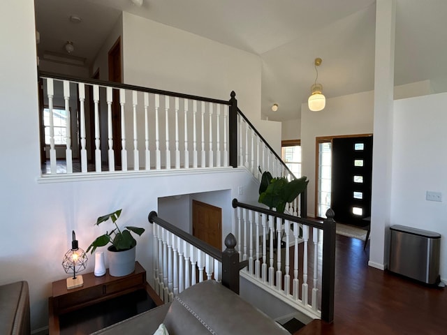 staircase featuring baseboards, wood finished floors, and a high ceiling