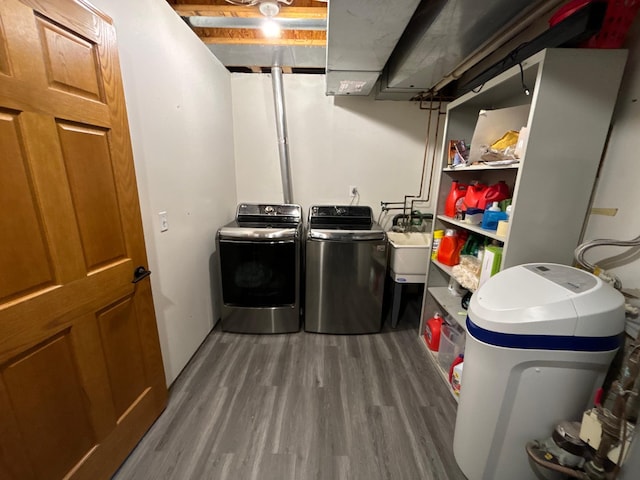 clothes washing area with independent washer and dryer, a sink, and wood finished floors