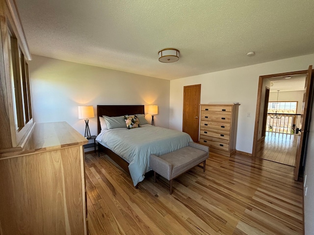 bedroom with a textured ceiling, baseboards, light wood finished floors, and a closet