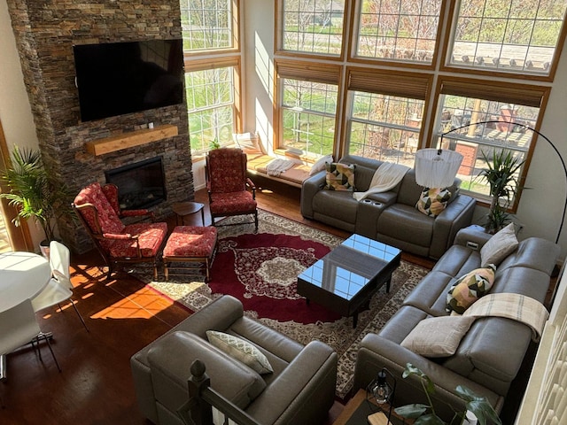living room with a fireplace, wood finished floors, and a towering ceiling