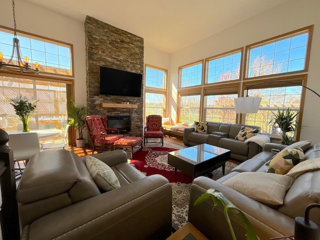 living room with wood finished floors, a high ceiling, a fireplace, and an inviting chandelier
