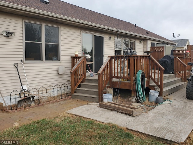 back of property featuring a shingled roof, a wooden deck, and fence