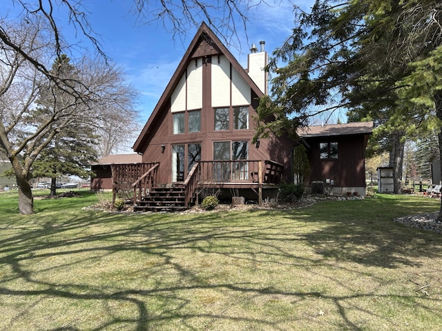 rear view of house with a chimney, a lawn, stairs, and a deck