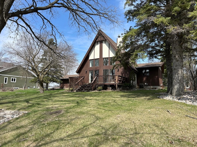 back of property featuring a wooden deck, a chimney, and a yard