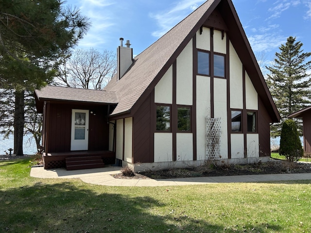 exterior space featuring a lawn, a chimney, a shingled roof, and stucco siding