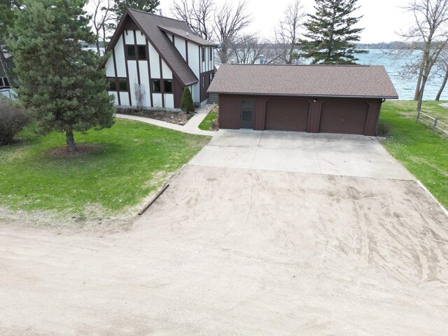 view of front of property featuring a detached garage, roof with shingles, and a front yard