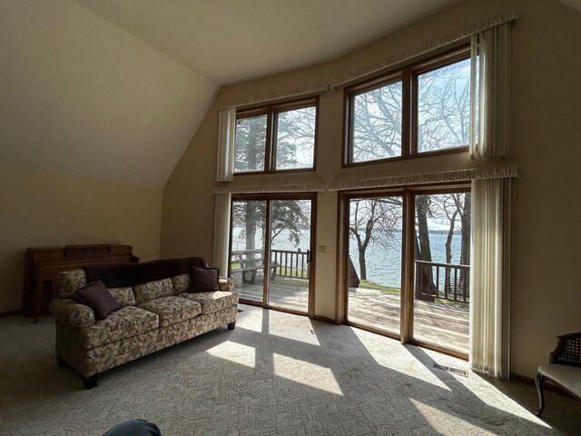 living room with vaulted ceiling, carpet floors, and a water view