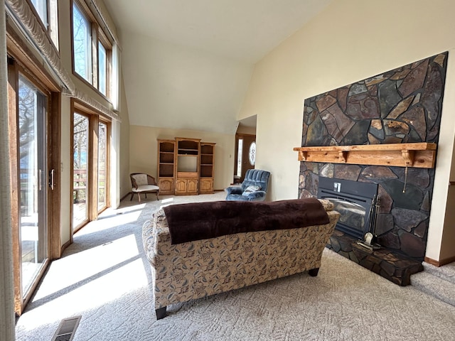 carpeted living area featuring visible vents, a fireplace, and high vaulted ceiling